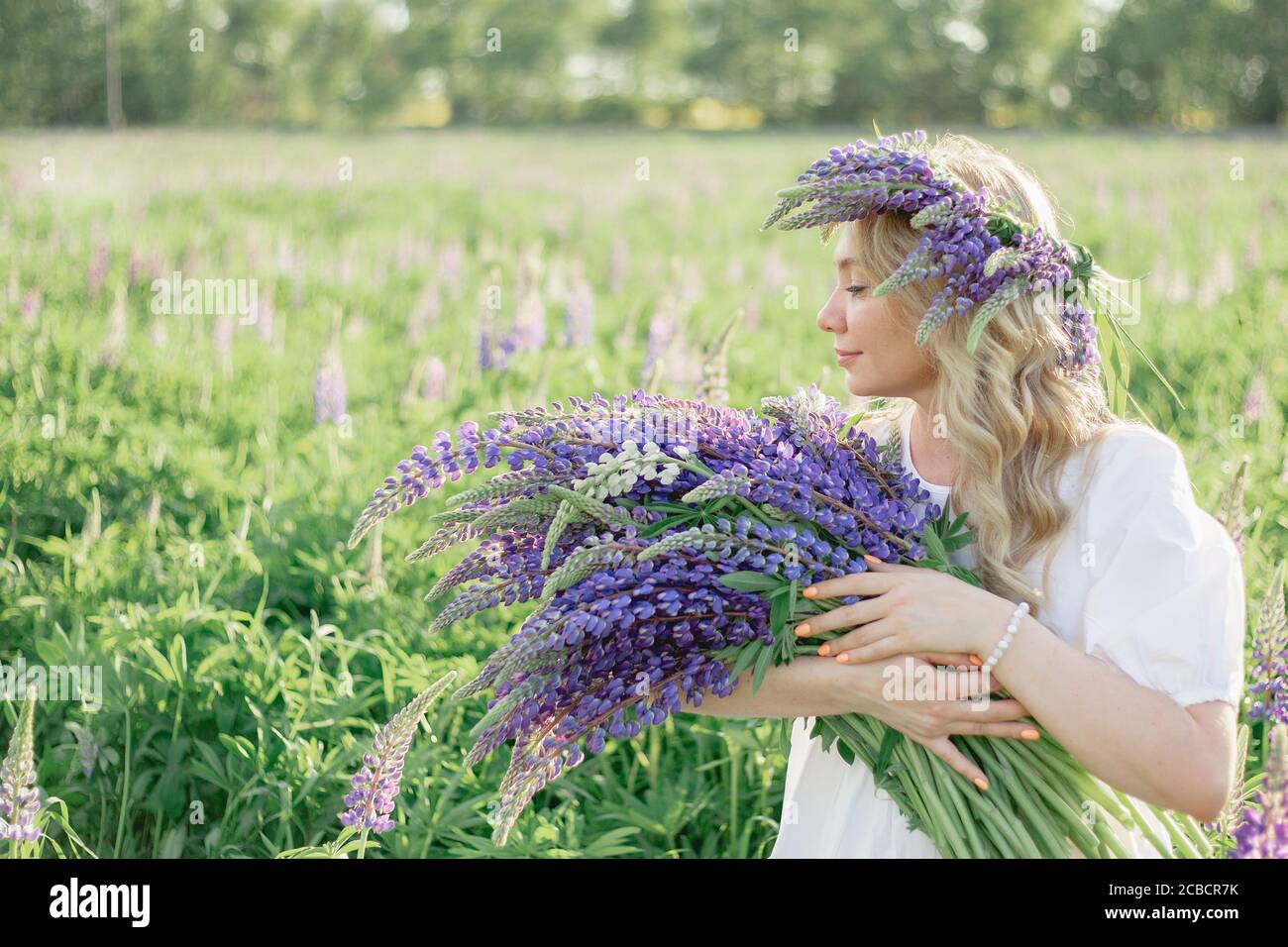 Porträt eines Mädchens mit einem Blumenstrauß in den Händen Lupinen, Blumenstrauß, Konzept der Allergie und Allergiekur, Spa, Erholung. Profil eines Mädchens mit Stockfoto