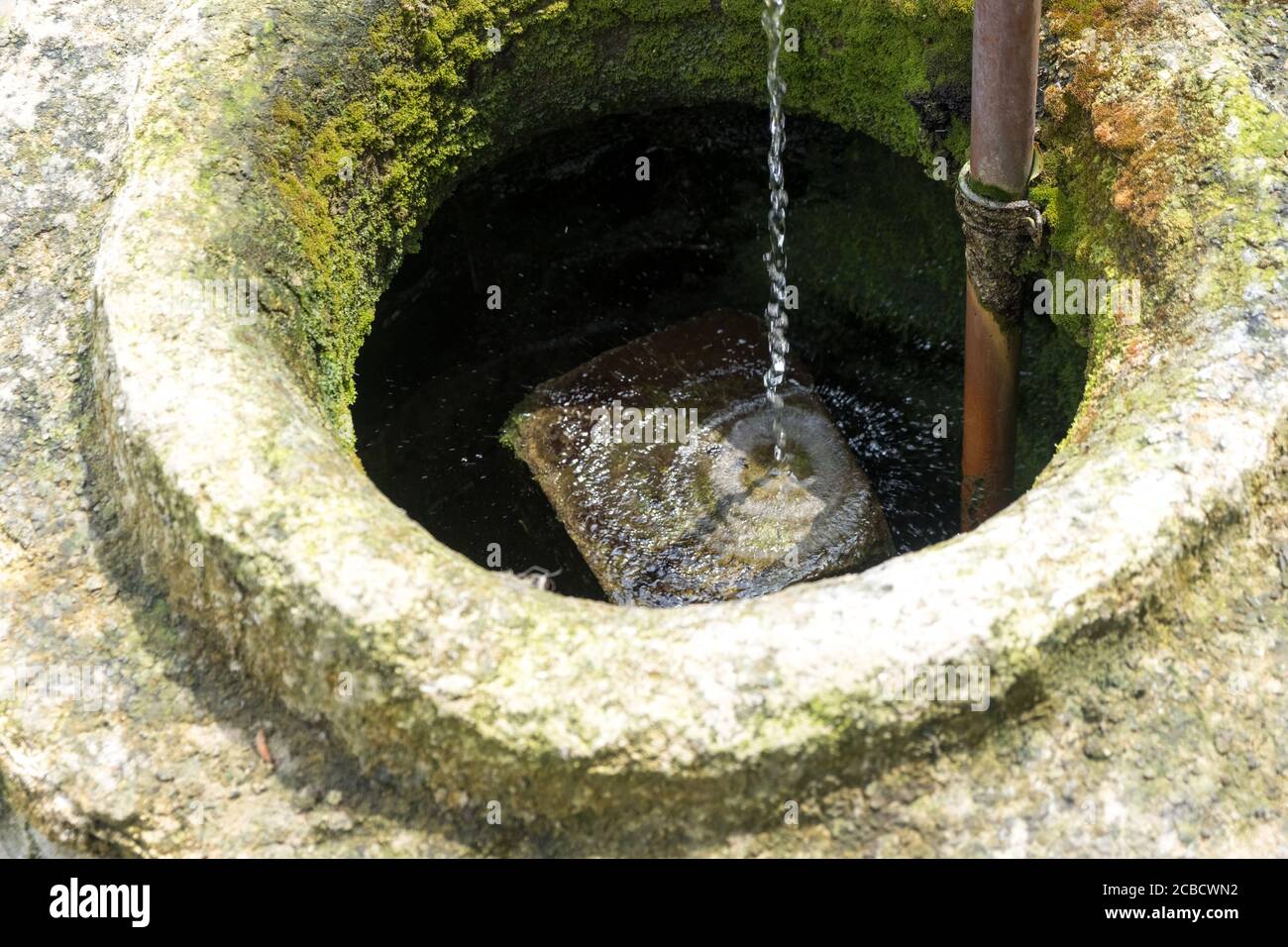 Sehr alter Brunnen, in dem sauberes Wasser fließt. Das Hotel liegt im Hof eines Landhauses Stockfoto