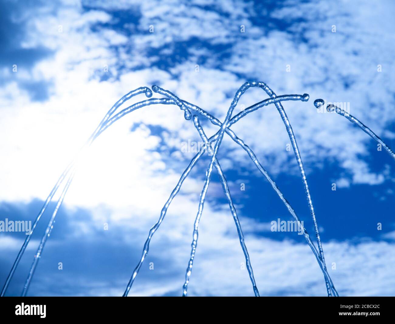 Brunnen frisches Wasser spritzen auf heißen Sommer Himmel Hintergrund. Klares Wasser oder Erfrischungsgetränk. Stockfoto