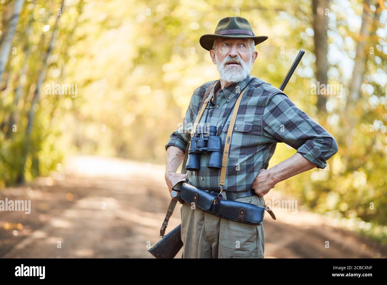 Bärtiger Mann steht nach der Jagd zur Ruhe, sucht nach neuer Trophäe. Sonniger Herbsthintergrund Stockfoto