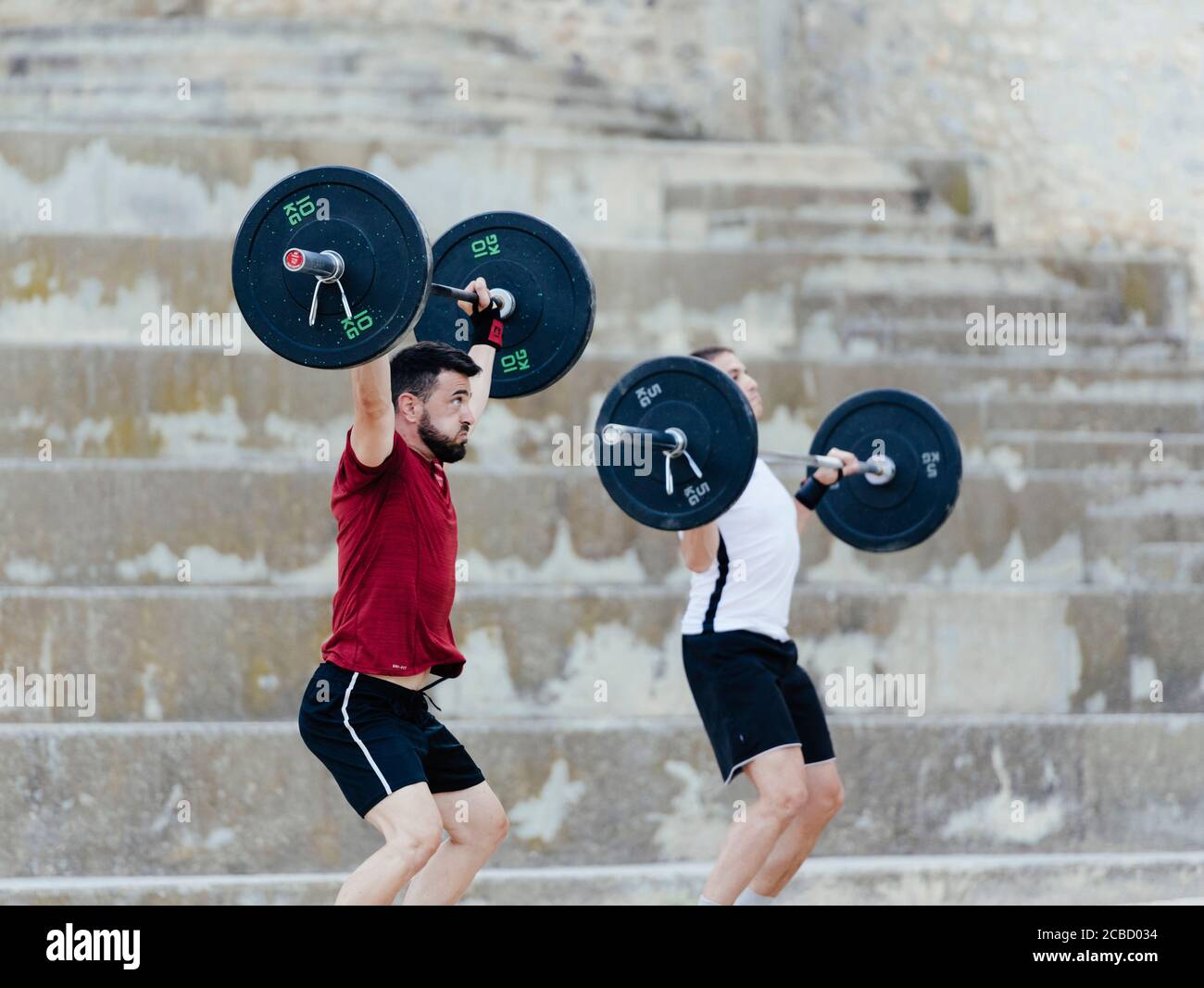 Zwei Gewichtheber heben Gewichte in einer städtischen Umgebung. Stockfoto