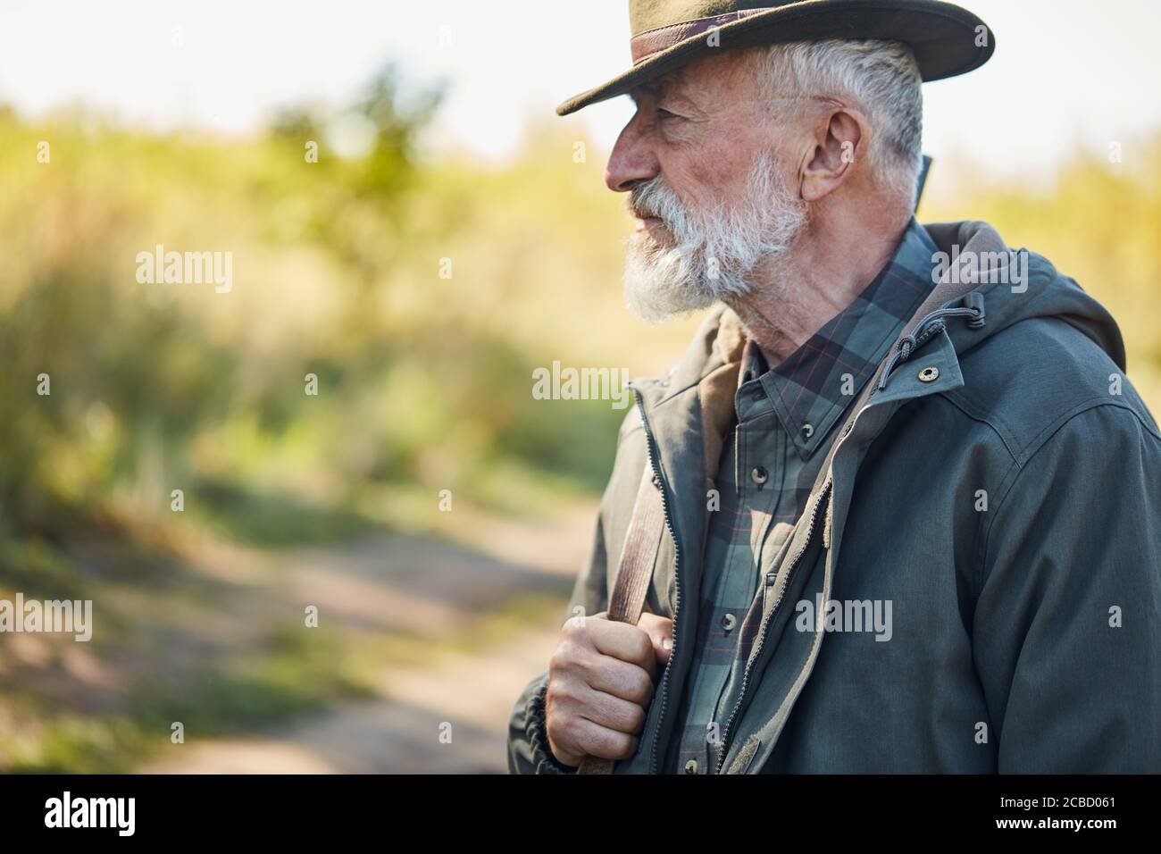 Seitenansicht auf reifer Jäger Mann mit Pistole, tragen Hut und Freizeitkleidung Stockfoto