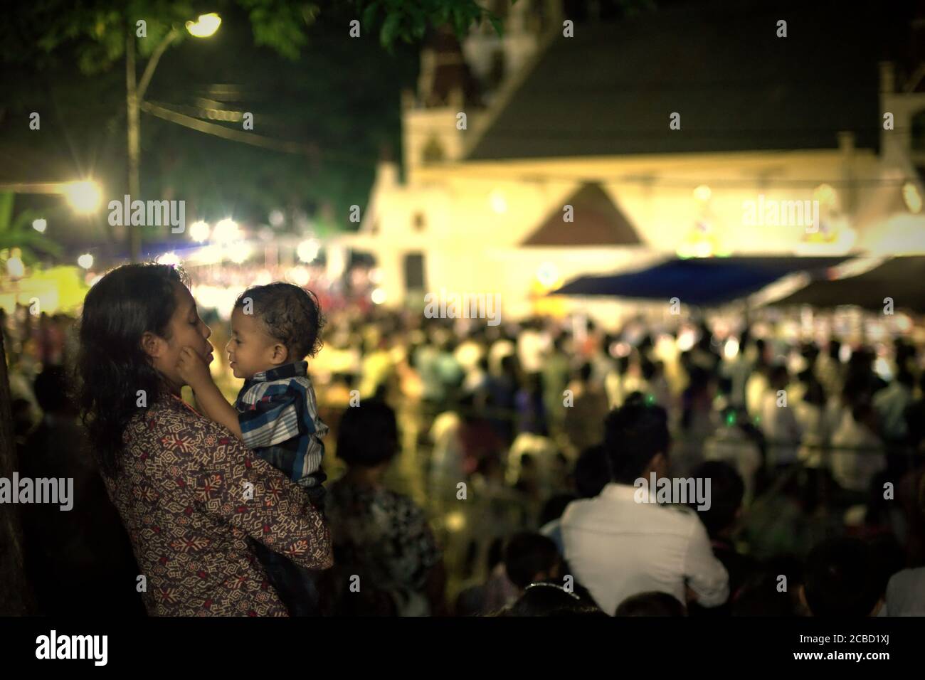 Larantuka, Indonesien. April 2015. Eine Mutter tröstet ihr Kind während des katholischen Gottesdienstes am Gründonnerstag in der Kathedrale von Larantuka, Insel Flores, Indonesien. Stockfoto