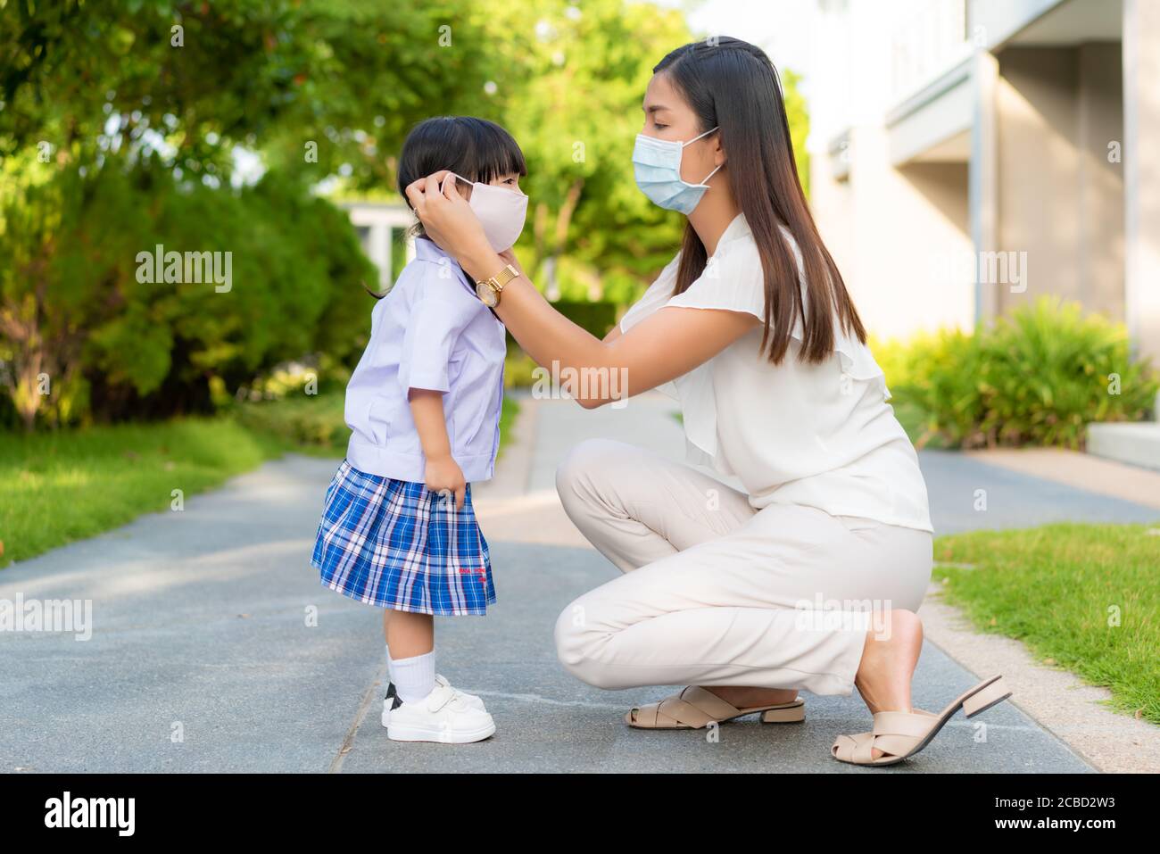 Asiatische Mutter helfen ihre Tochter trägt medizinische Maske zum Schutz Covid-19 oder Coronavirus Ausbruch im Dorfpark zu gehen vorbereiten Zurück zur Schule Stockfoto