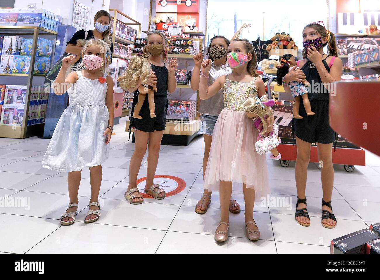 New York City, USA. August 2020. Eine Gruppe junger Grillen, die alle Masken  tragen, sehen sich bei einem Geburtstagsausflug einen Zaubertrick im neu  eröffneten, berühmten Spielwarenladen FAO Schwarz im Rockefeller Center in