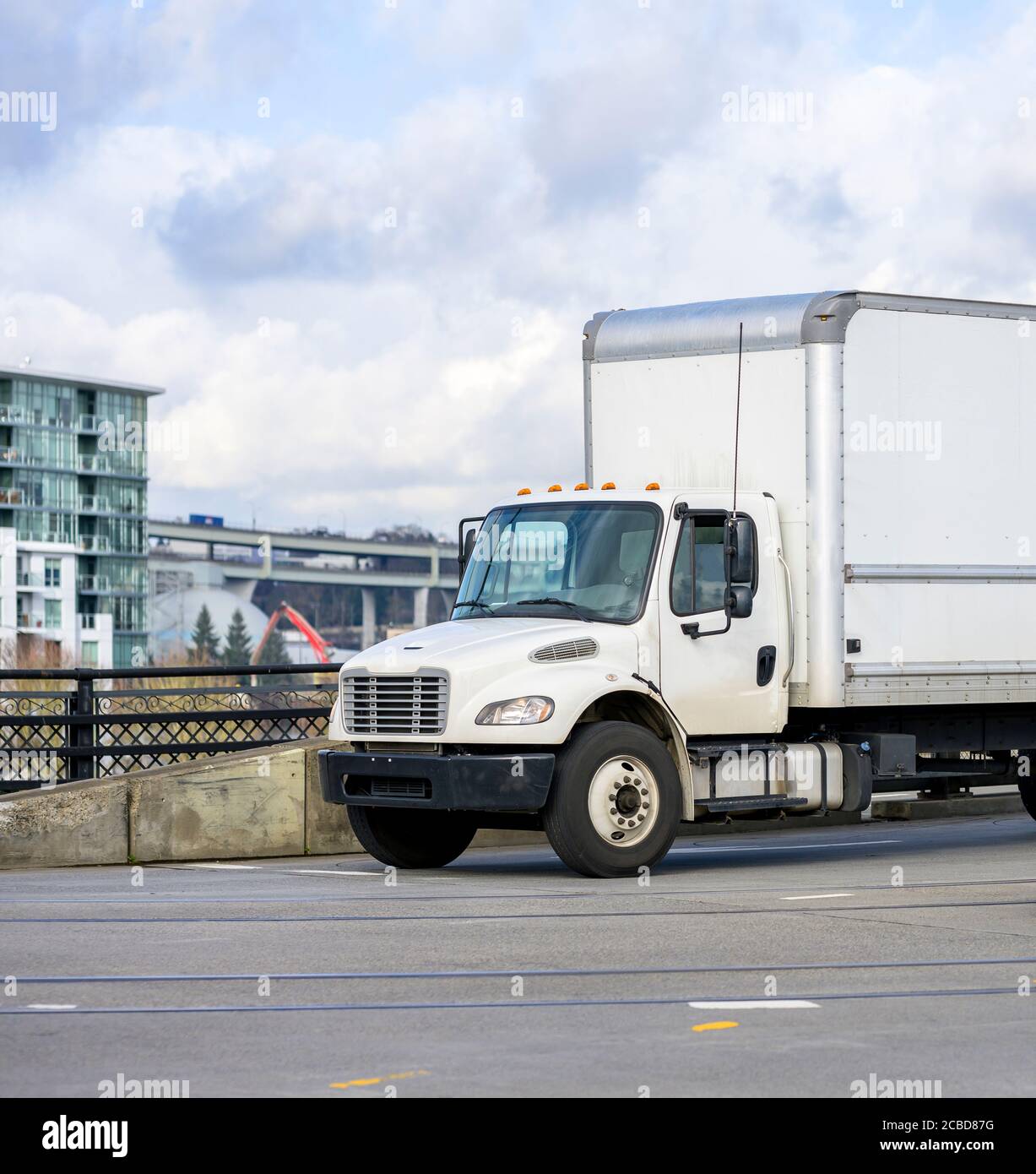Mittlere Größe kompakte leistungsstarke Rig Semi-Truck mit Box Cargo Anhänger für lokale Lieferungen, die auf der Brücke auf dem fahren City Street Stockfoto
