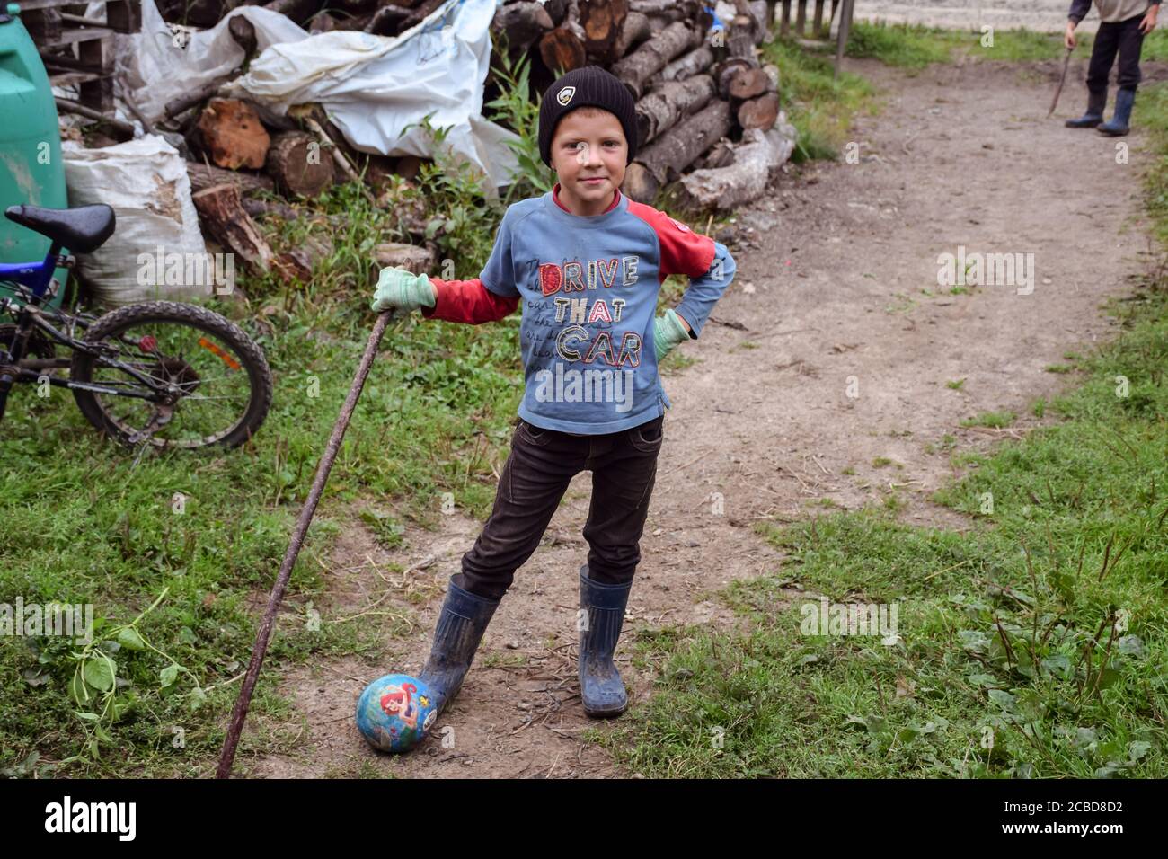 Maramures / Rumänien - 28. August 2019: Porträt eines freundlichen rumänischen Jungen, der Baseball mit Holzstock in ländlicher Umgebung spielt Stockfoto
