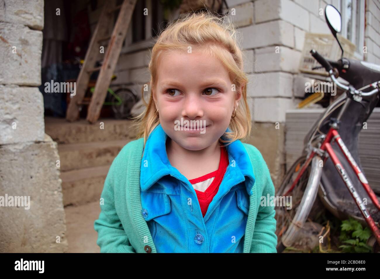 Maramures / Rumänien - 28. August 2019: Lustige kleine blonde Mädchen lächelt zu Hause in rumänischen Dorf Stockfoto