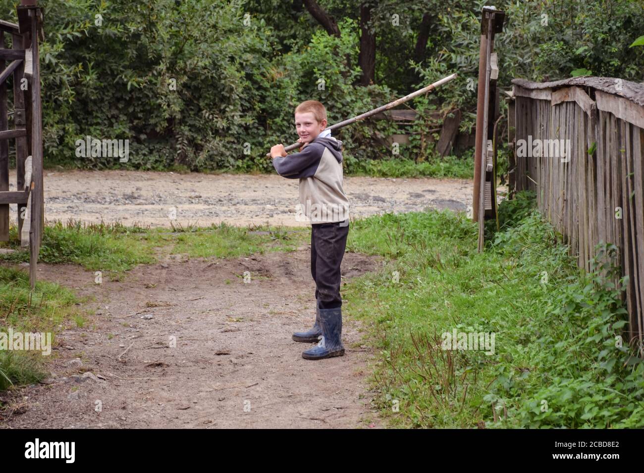 Maramures / Rumänien - 28. August 2019: Porträt eines freundlichen rumänischen Jungen, der Baseball mit Holzstock in ländlicher Umgebung spielt Stockfoto