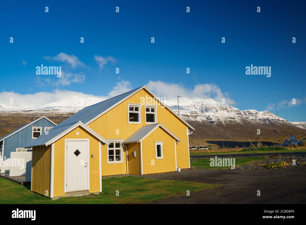 Lebendiges isländisches Haus vor der Bergkette unter dem Blau Himmel von Seydisfjordur Stockfoto