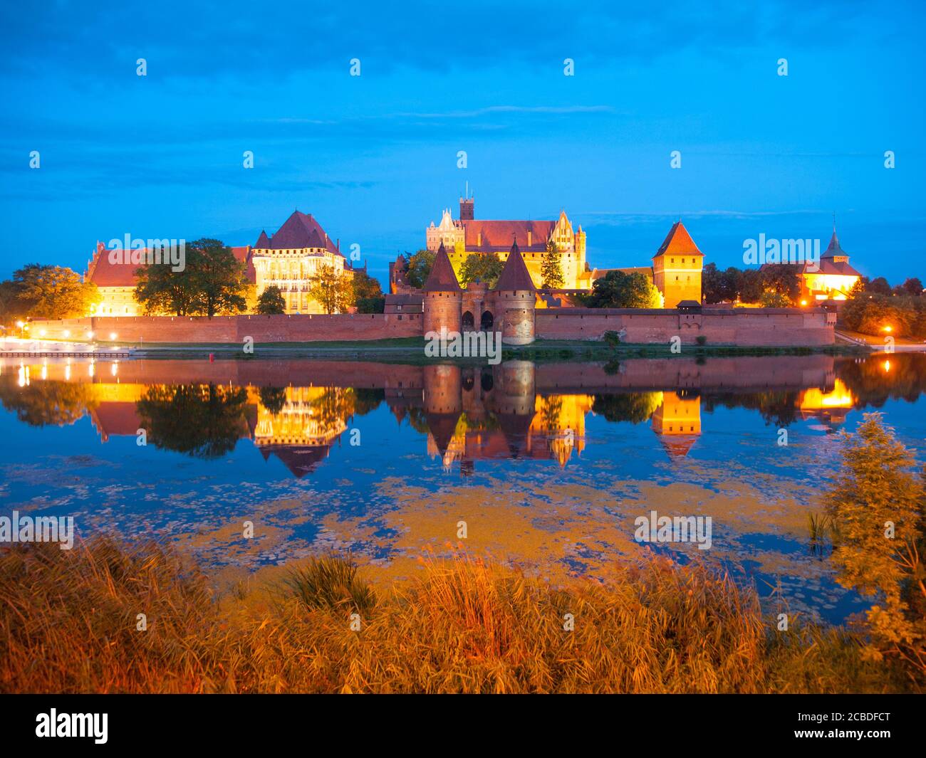 Malbork Schloss bei Nacht mit Reflexion in Nogat Fluss, Polen Stockfoto