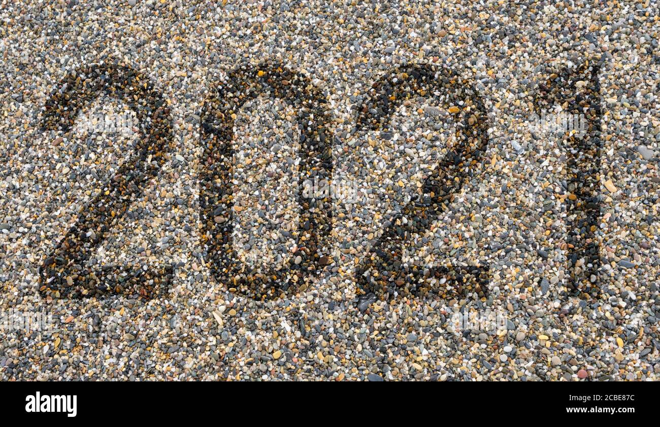 Text mit der Nummer des Jahres 2021 auf kleinen bunten Steinen am Strand. Frohes Neues Jahr 2021. Stockfoto