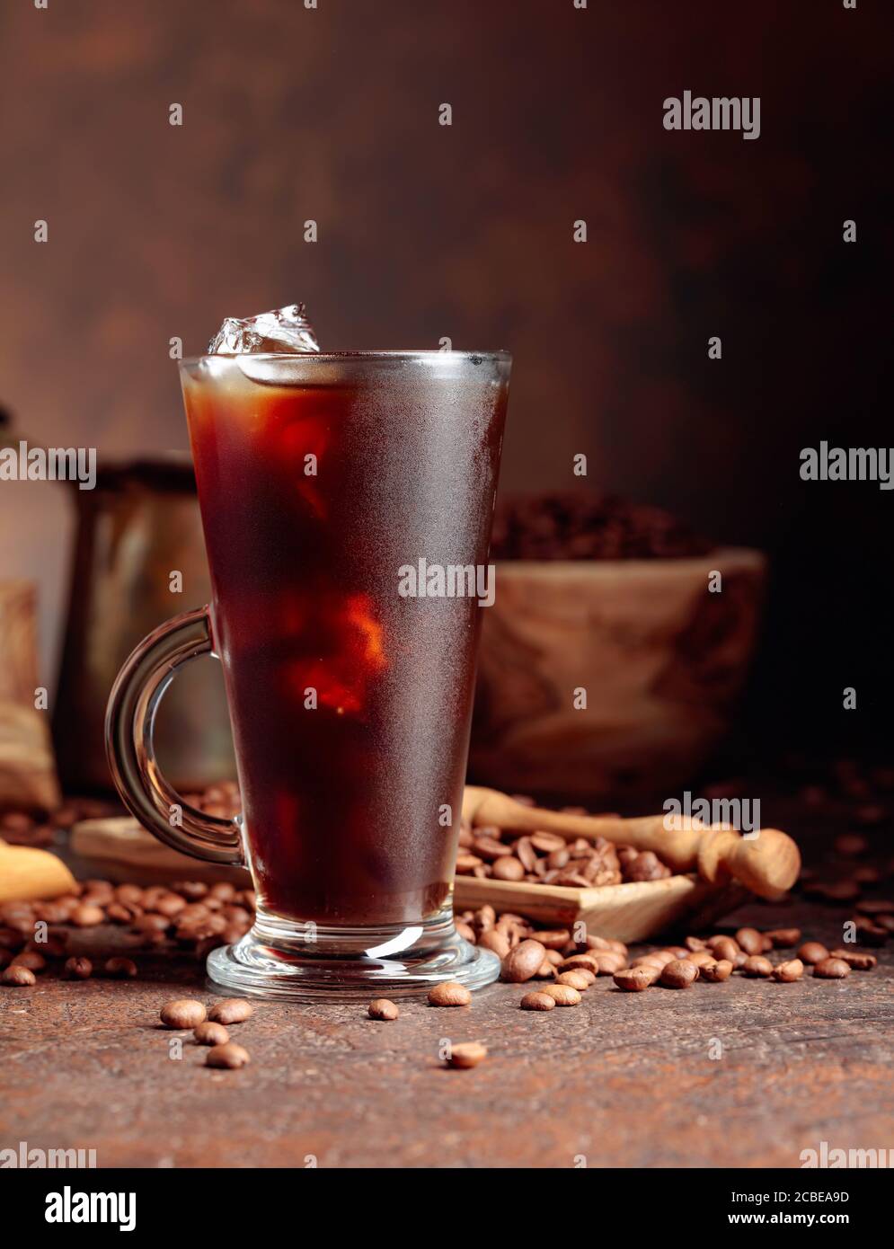 Eiskaffee in gedämpftem Glas und Kaffeebohnen auf einem alten braunen Tisch mit Küchenutensilien. Speicherplatz kopieren. Stockfoto