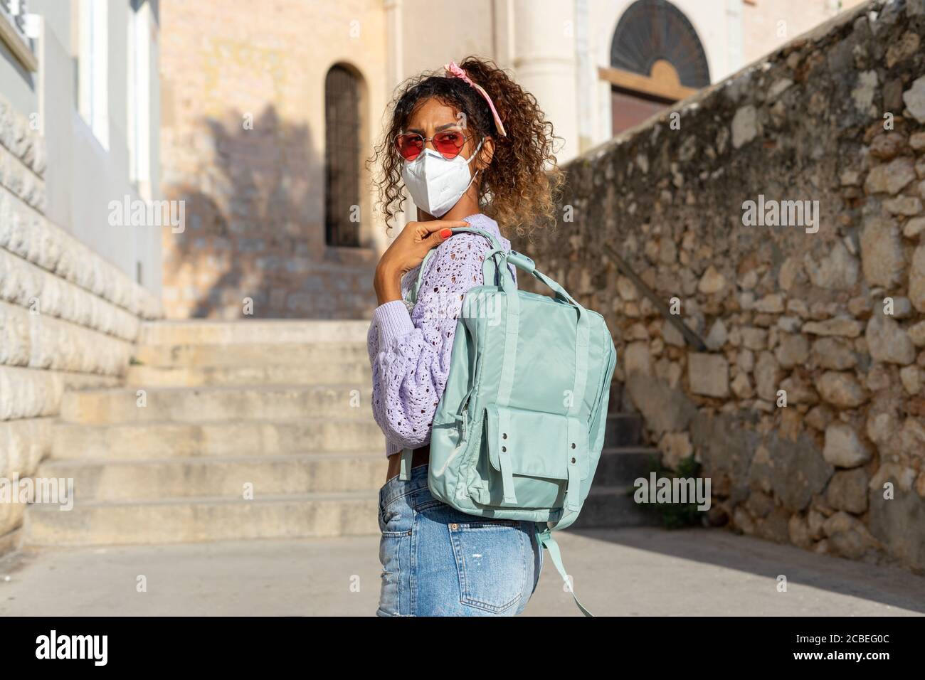 Porträt einer attraktiven jungen schwarzen Frau, die mit Rucksack und Maske läuft. Sehenswürdigkeiten Stockfoto