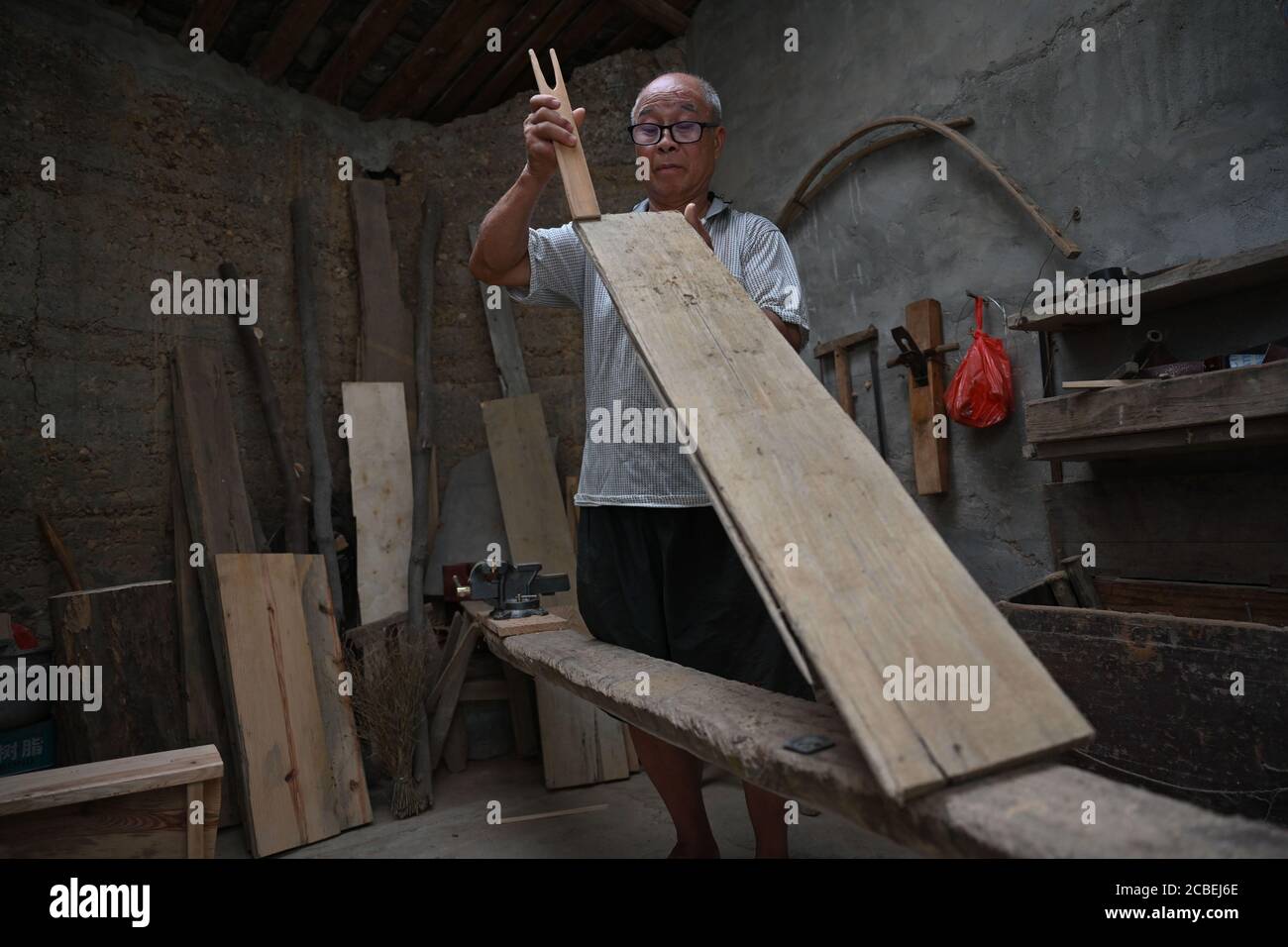 (200813) -- CHANGTING, 13. August 2020 (Xinhua) -- der Tischler-Veteran Li Shishui bereitet im Dorf Xinqiao der Gemeinde Xinqiao, Bezirk Changting, südöstlich der Provinz Fujian in China, eine Abfallplanke für die Herstellung von Holzspielzeug vor, 12. August 2020. Dandan wurde vor kurzem zum Neid aller Kinder in seinem Dorf -- das 18 Monate alte Kleinkind hatte ein großes Baby Auto aus Holz von seinem Opa in Handarbeit erhalten. Das besondere Geschenk mit beweglichen Teilen, die an die Beine einer Gottesanbeterin erinnern, ging viral online, als die Eltern von Dandan ein Video davon auf der Social-Networking-Plattform teilten. Der Schöpfer des Holzspielzeugs, Li shis Stockfoto