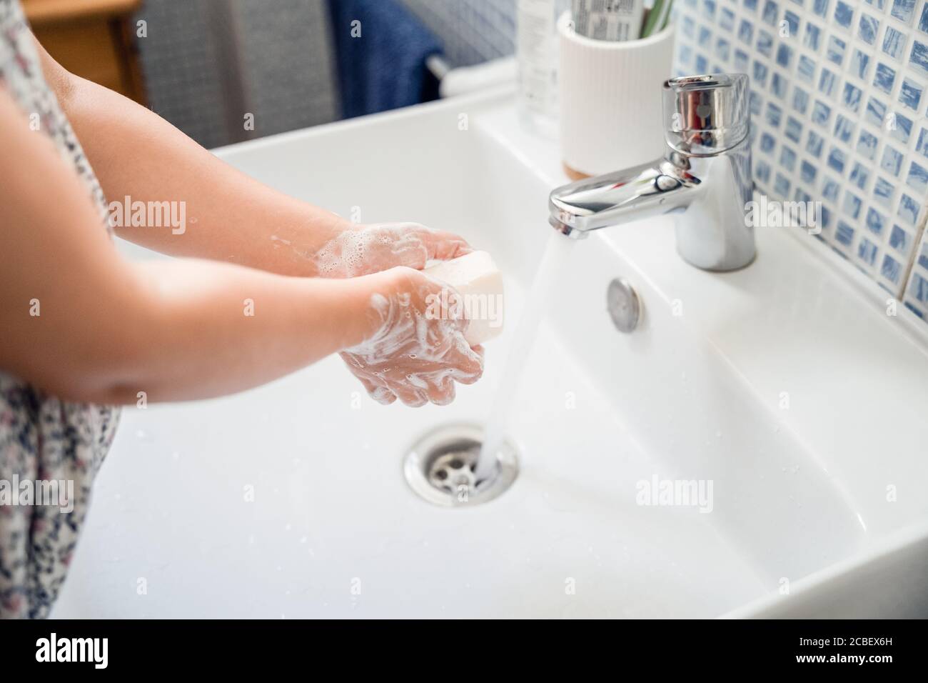 Kleines Mädchen wäscht die Hände mit einem Stück Seife im Waschbecken Unter fließendem Leitungswasser Stockfoto