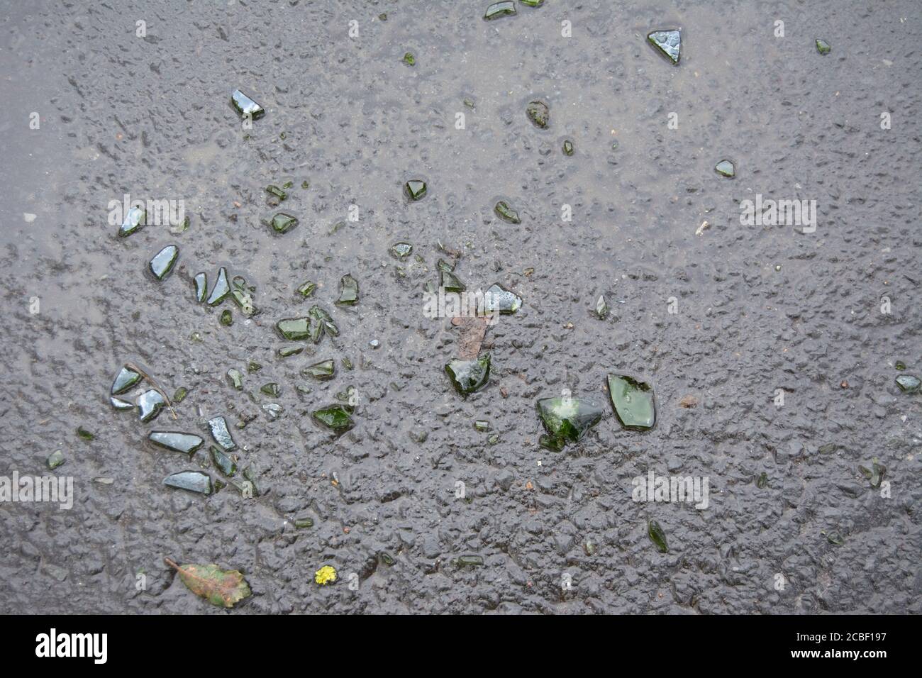Klare und grüne Glasscherben auf nasser Fahrbahn in twickenham, middlesex, england Stockfoto