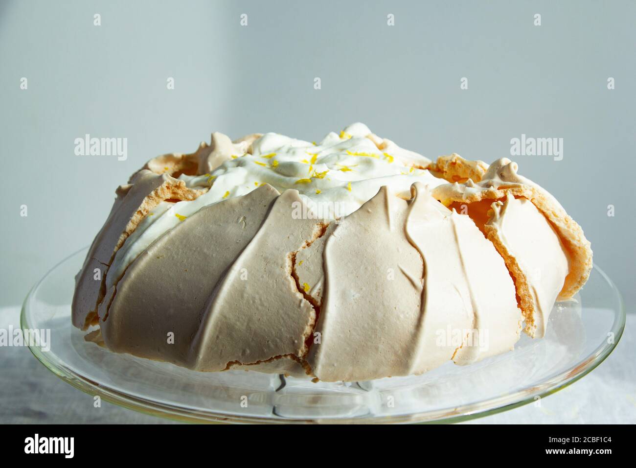 Hausgemachte Baiser Pavlova mit Schlagsahne auf Glas-Kuchen-Stand. Sommerkuchen. Knusprige Nachspeise. Nahaufnahme Stockfoto