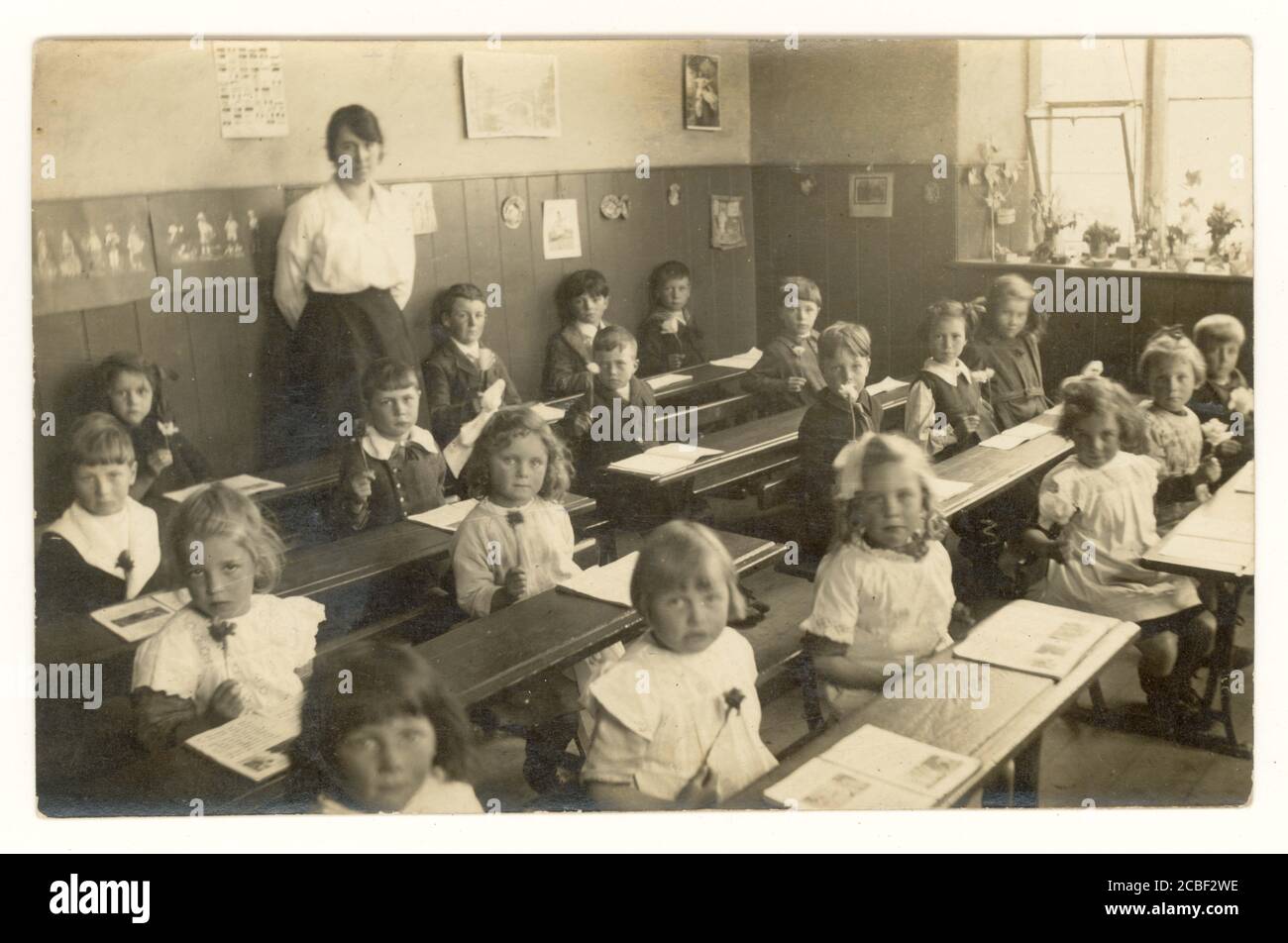 Postkarte aus der Zeit des 1. Weltkriegs von Schulkindern mit Blumen, im Klassenzimmer mit Lehrer, um 1915, Großbritannien Stockfoto