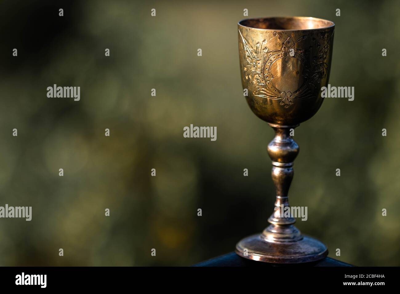 Elegante, goldene, Vintage-Tasse auf verschwommenem Hintergrund. Heiliger Gral. Stockfoto