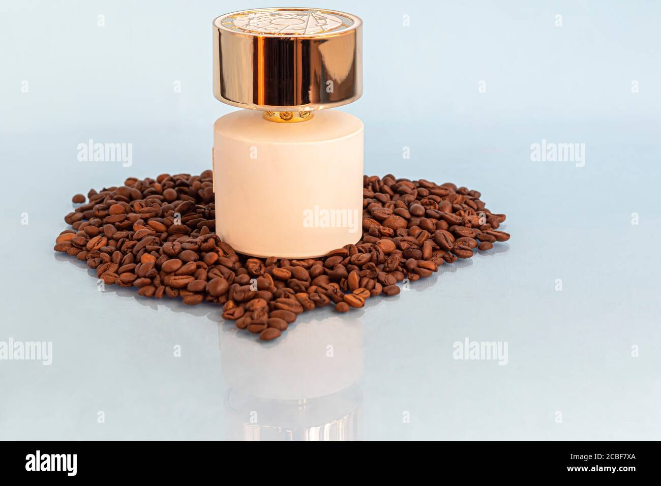 Weiße Flasche mit Damenparfüm. Umgeben von Kaffeebohnen auf hellem Hintergrund. Speicherplatz kopieren Stockfoto