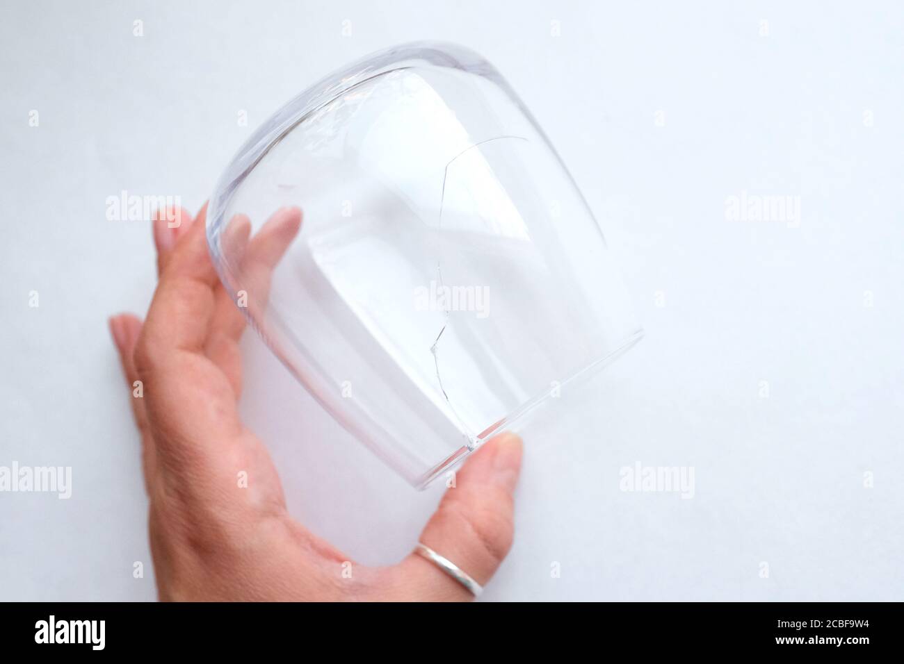 Ein großer dünner Riss im Glas. Hält ein verdorbenes Glas in der Hand. Blick von oben. Stockfoto