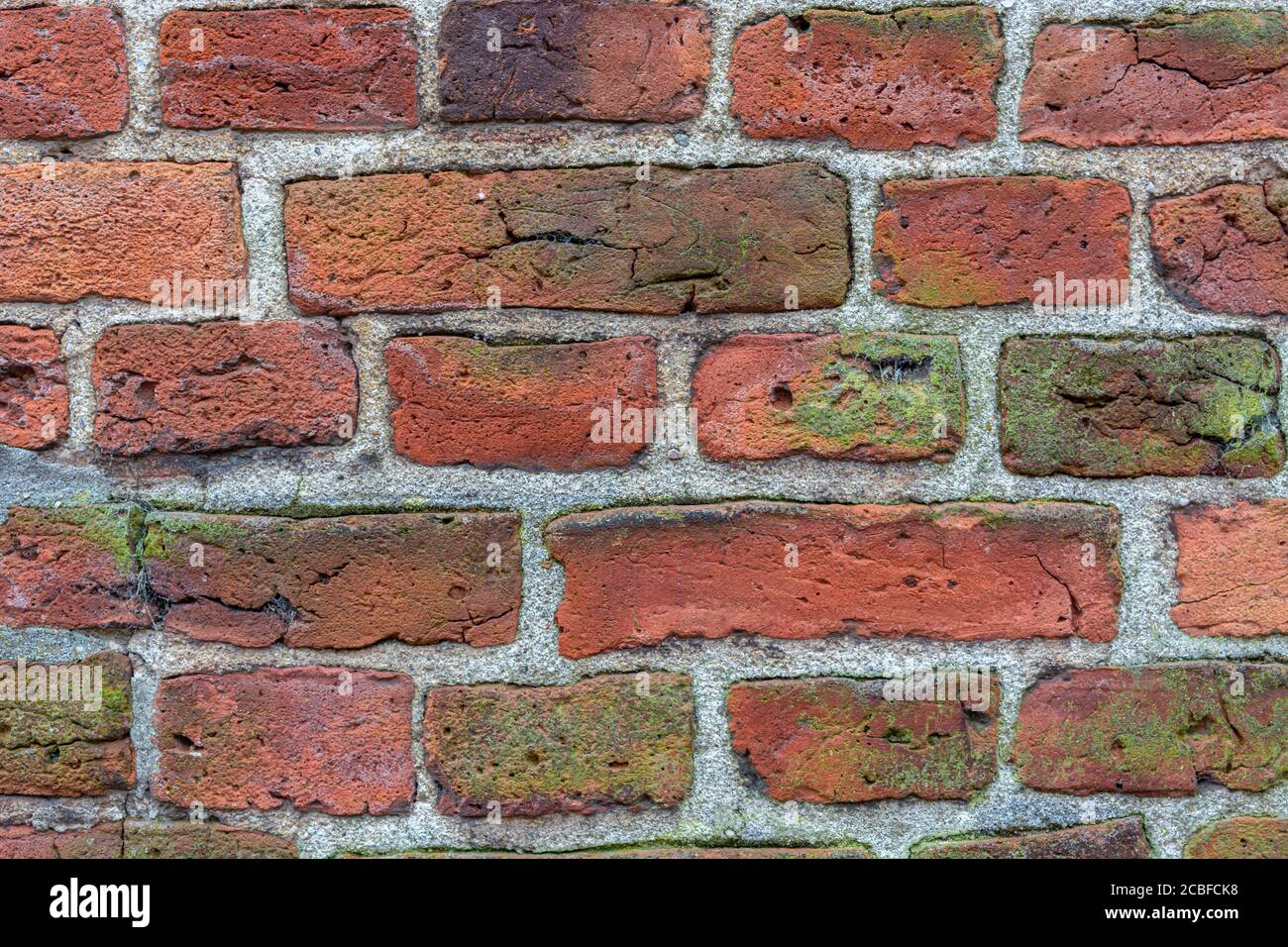 Hintergrund altes Mauerwerk aus rotem Backstein. Putz, Beton, Zement. Risse, Abschälen, Hohlräume. Nahaufnahme Stockfoto