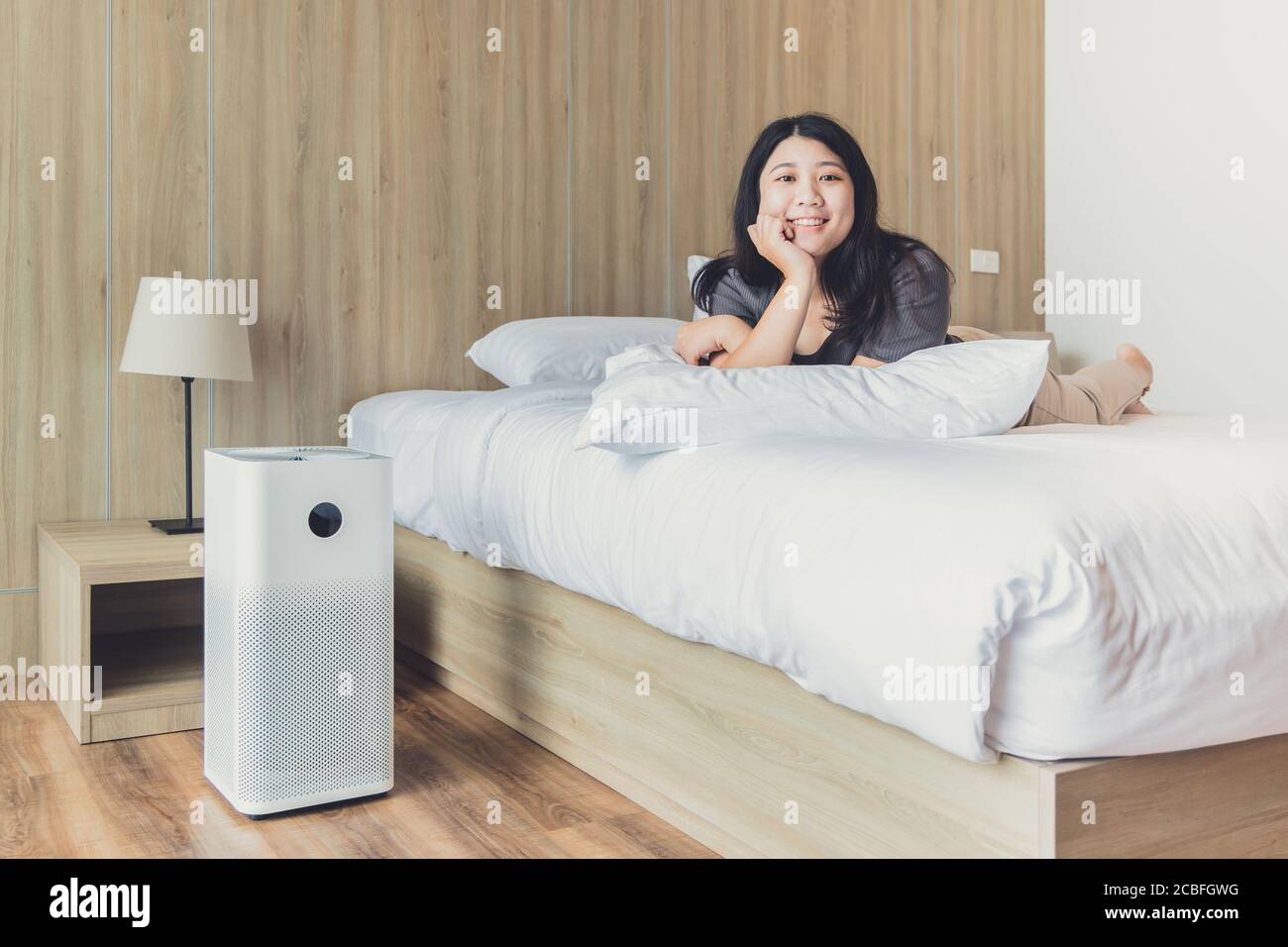 Frau zu Hause Schlafzimmer glücklich genießen mit Luftreiniger für Reinigen Sie PM 2.5 Staubverschmutzung und bleiben Sie gesund Stockfoto