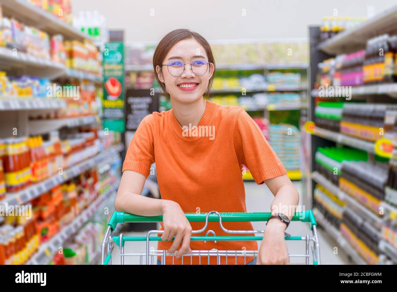Asiatische Frau glücklich Einkaufen in Einkaufszentrum Griff Warenkorb Herum mit Supermarkt Regal Stockfoto