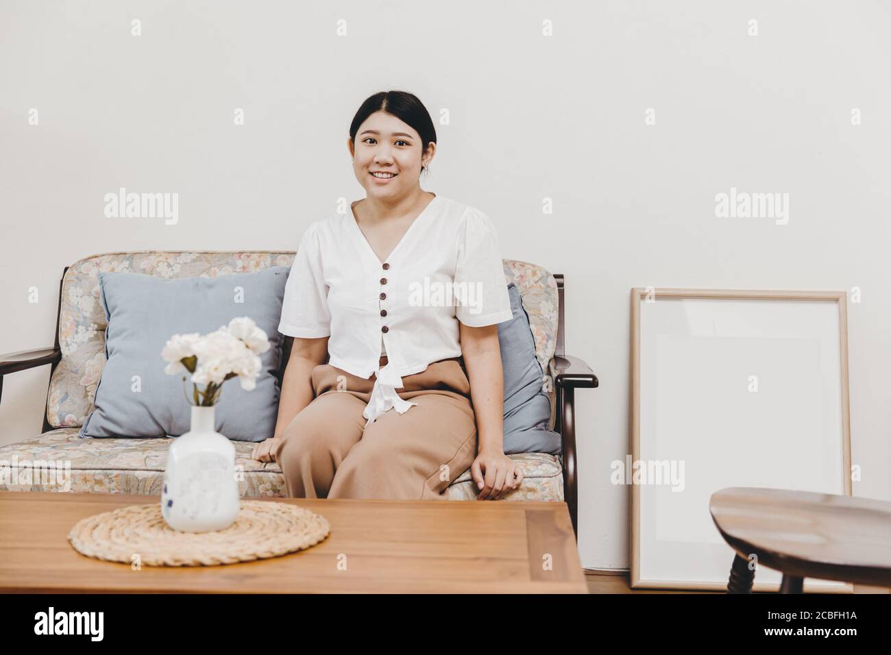 Plump und gesunde Hausfrau sitzen im Wohnzimmer warm lächelnd, Blick auf die Kamera Stockfoto