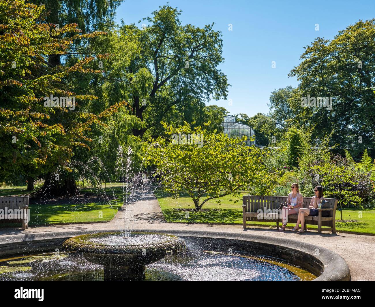 Zwei junge Frau neben dem Pool mit Brunnen, University of Oxford Botanical Gardens, Oxford, Oxfordshire, England, Großbritannien, GB. Stockfoto