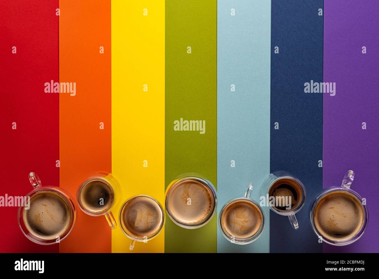 Reihe von Thermoglas-Tassen mit frischem schwarzem Espresso und Americano-Kaffee. Bunt gestreifter Hintergrund in LGBT-Farben mit Papiertextur. Direkt darüber Stockfoto