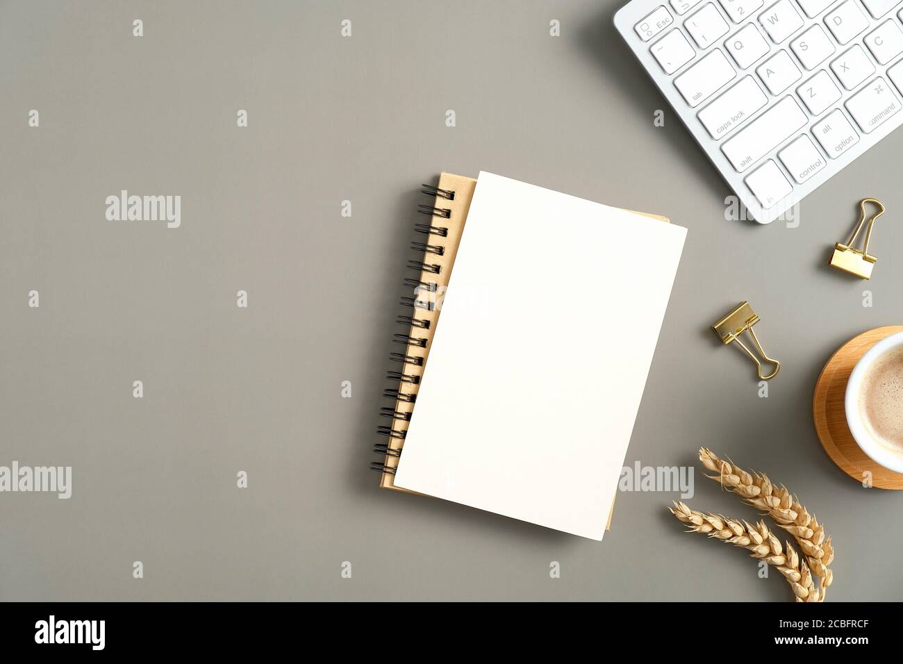 Flacher Bürotisch mit Blick von oben. Moderner Arbeitsplatz mit Notebook, Tastatur, Kaffeetasse, Verbrauchsmaterial und leerem Papier. Moderner minimalistischer Stil Stockfoto