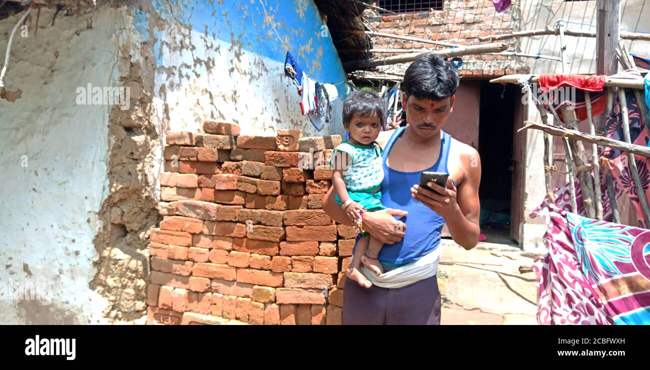 DISTRIKT KATNI, INDIEN - 20. AUGUST 2019: Ein indischer Dorfmensch, der Smartphone mit Baby hält, Konzept für das digitale Lernen asiatischer Menschen. Stockfoto