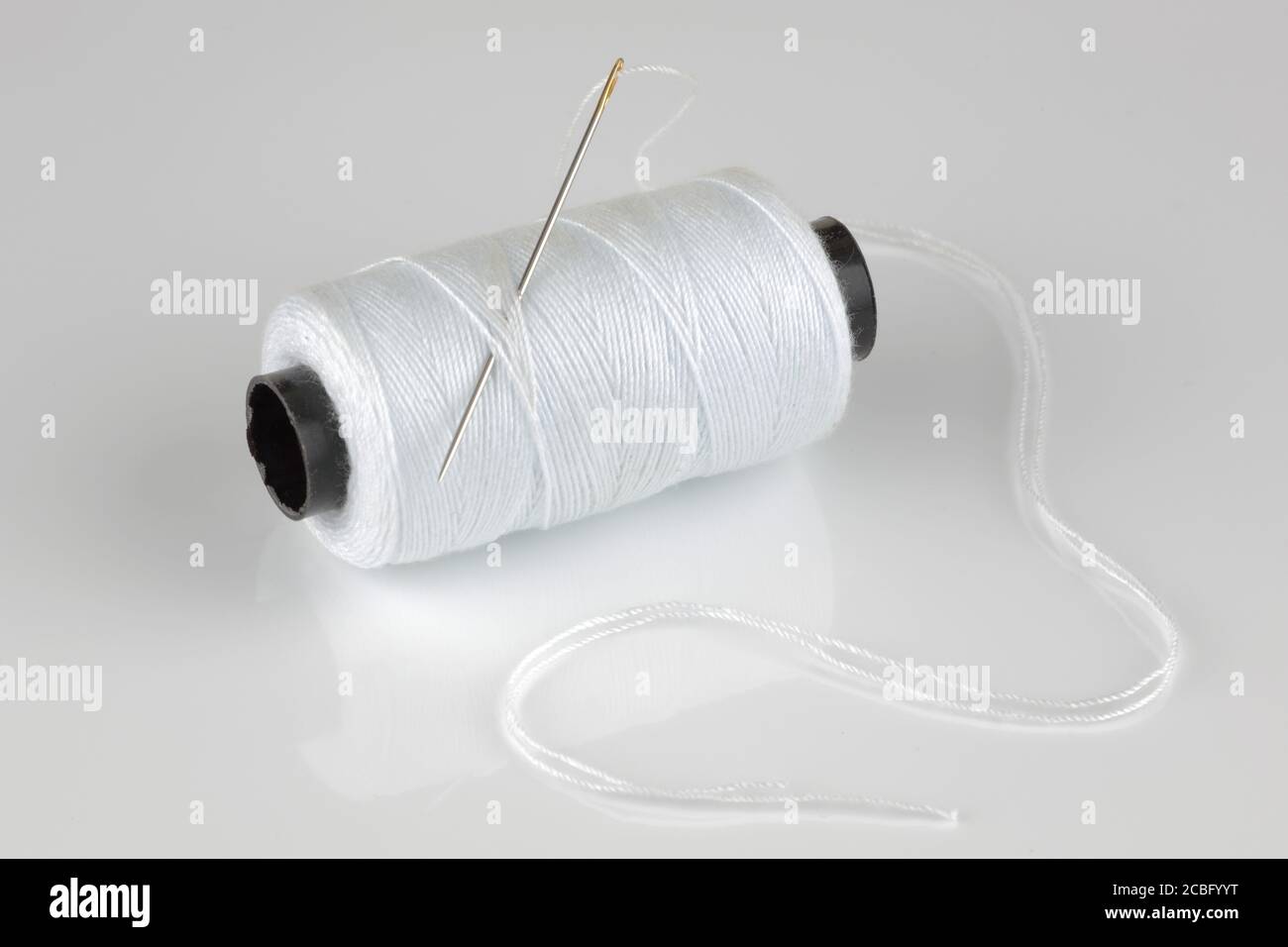 Weiße Baumwollrolle und Nadel mit Reflexion Stockfoto