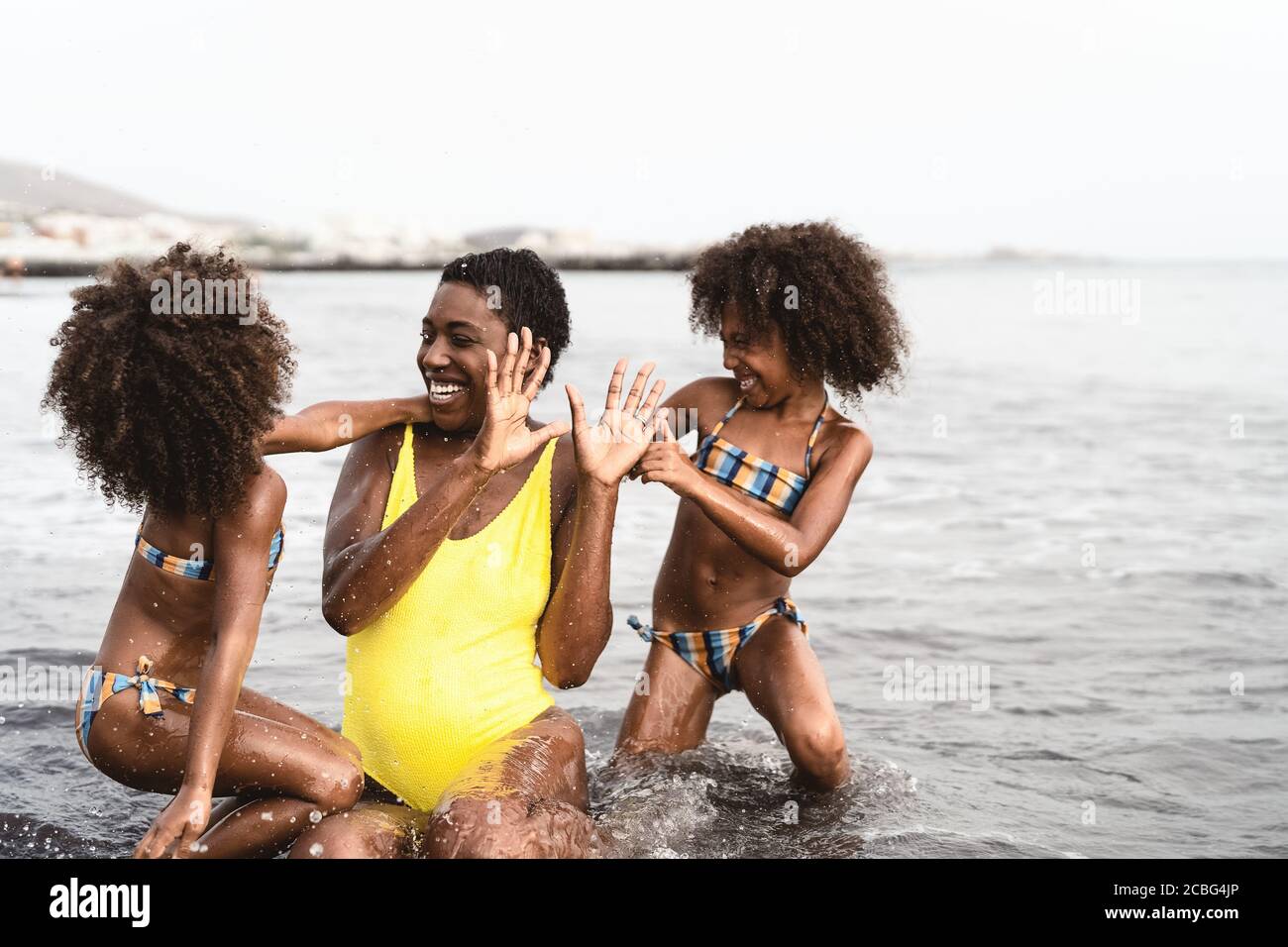 Glückliche afrikanische Familie spielt am Strand während der Sommerferien - Afro-amerikanische Leute, die Spaß im Urlaub haben Stockfoto