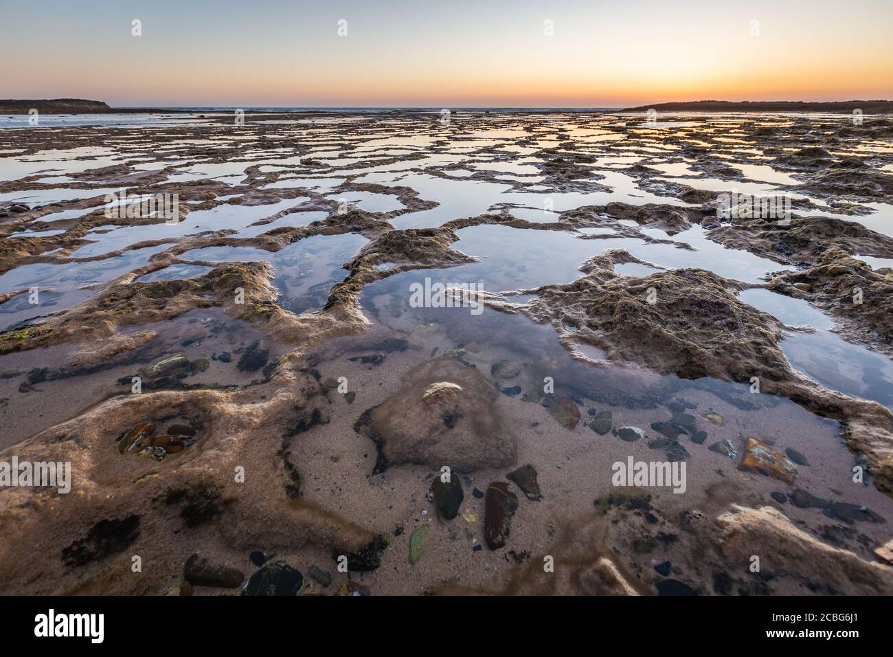 Meereslandschaft von Vila Nova Milfontes bei Ebbe, bei Sonnenuntergang Stockfoto