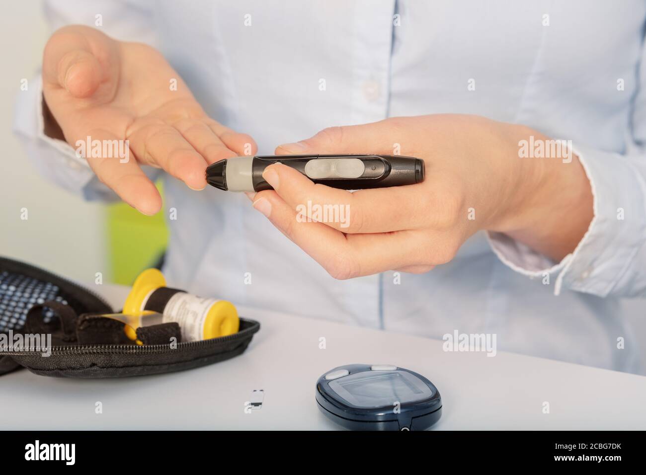Frauenhände machen einen Zuckertest für Diabetes sitzend vorbei Die Tabelle Stockfoto