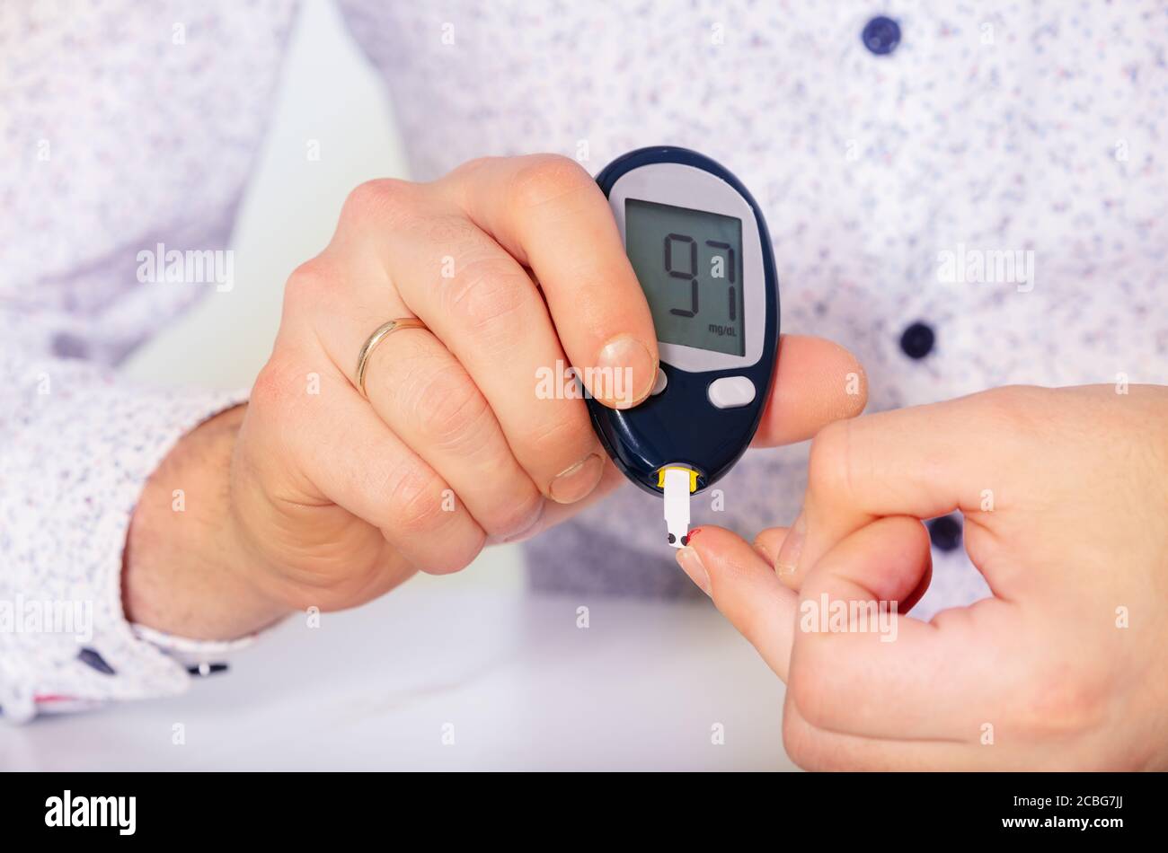 Die Hände des Menschen machen einen Zuckertest für Diabetes sitzen vorbei Die Tabelle Stockfoto