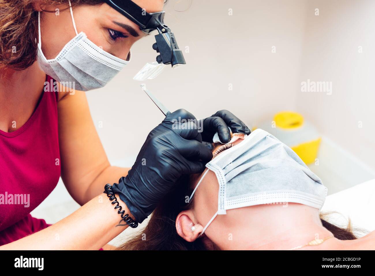Kosmetikerin in Beauty-Center Durchführung einer Augenbraue Behandlung an Kunden, mit Masken während der neuen Normalität Stockfoto