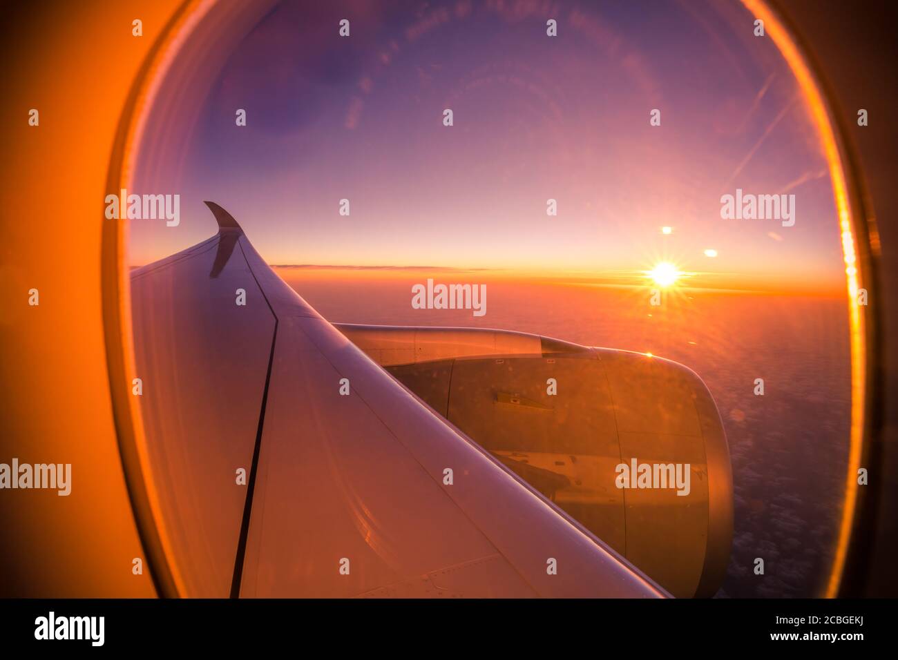 Wunderschöne malerische Aussicht auf den Sonnenuntergang durch das Flugzeugfenster. Schöner Sonnenuntergang, Himmel die Ansicht von oben, Flugzeug fliegende Ansicht von innen Fenster Flugzeuge Stockfoto
