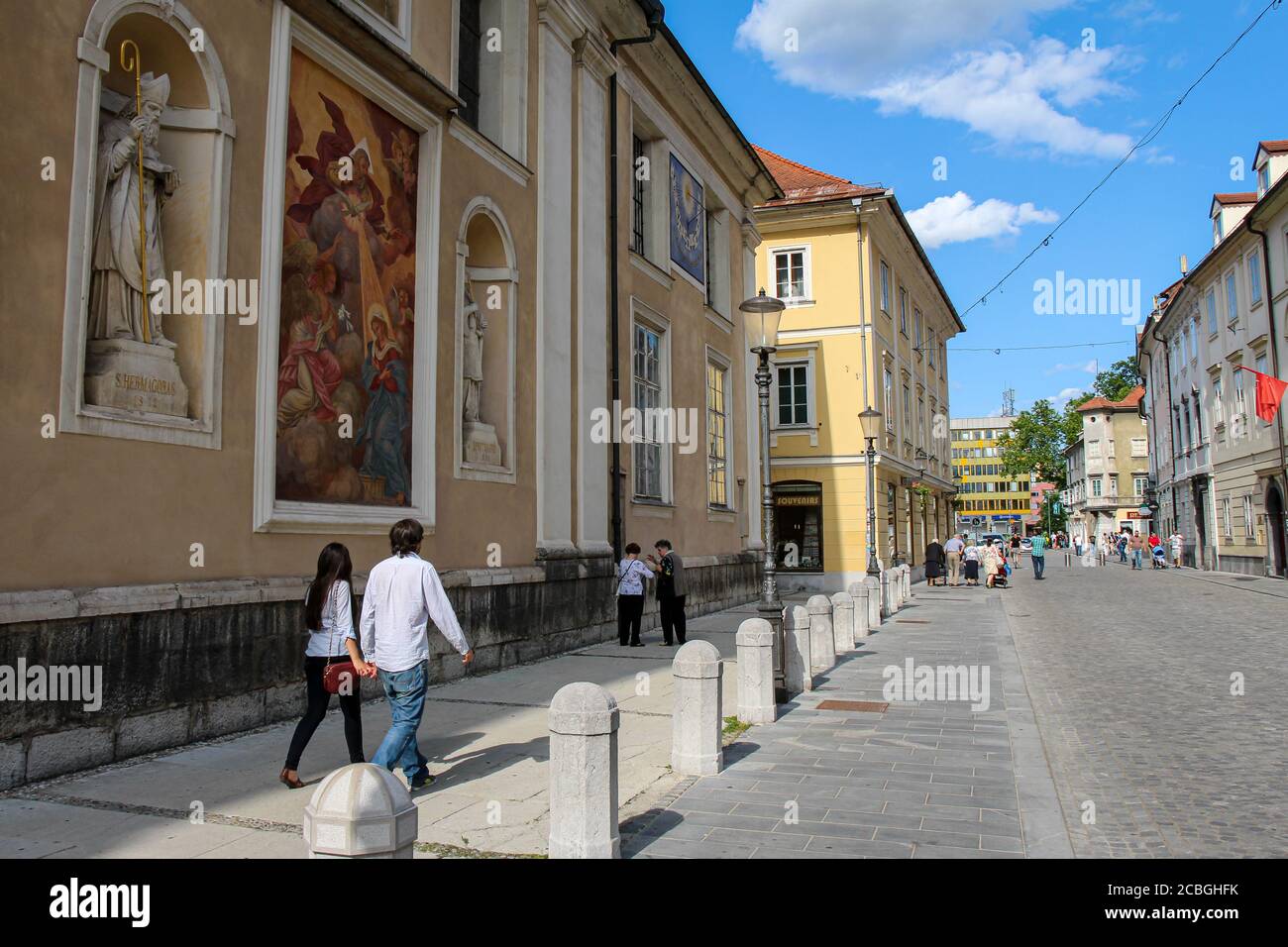Ljubljana, Slowenien - 16. Juli 2018: Touristen, die an der Mauer der Kathedrale von Ljubljana auf der Ciril-Metodov Trg, Slowenien, vorbeigehen Stockfoto