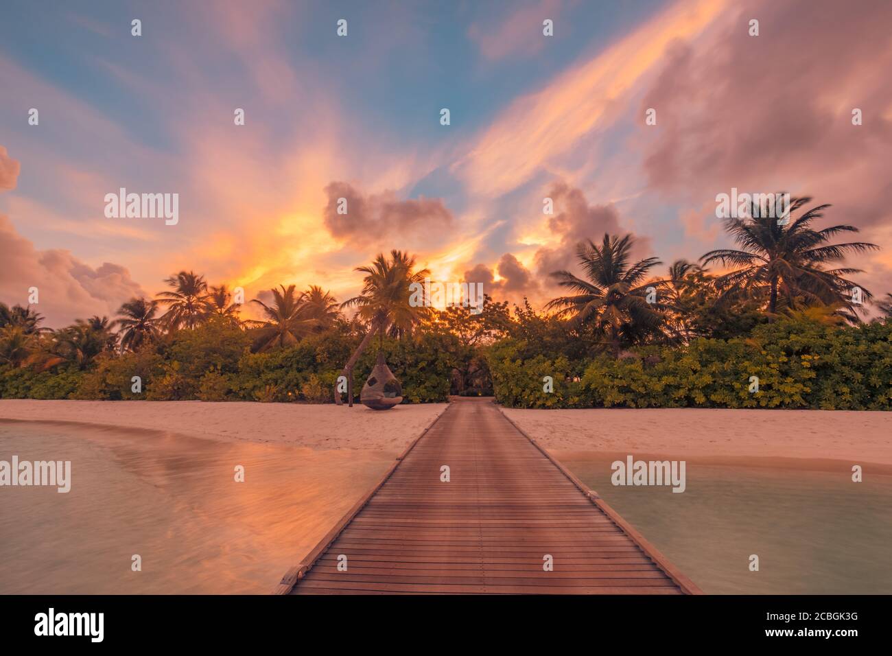 Sonnenuntergang auf der Insel der Malediven, Luxus-Wasservillen-Resort und hölzerner Pier. Schöne Himmel Wolken und Palmen Strand Hintergrund für Sommerurlaub Stockfoto
