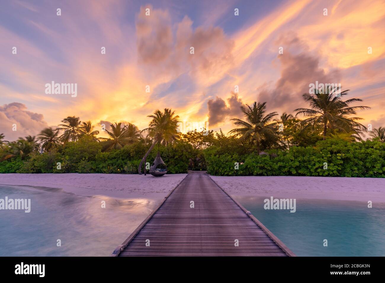 Sonnenuntergang auf der Insel der Malediven, Luxus-Wasservillen-Resort und hölzerner Pier. Schöne Himmel Wolken und Palmen Strand Hintergrund für Sommerurlaub Stockfoto