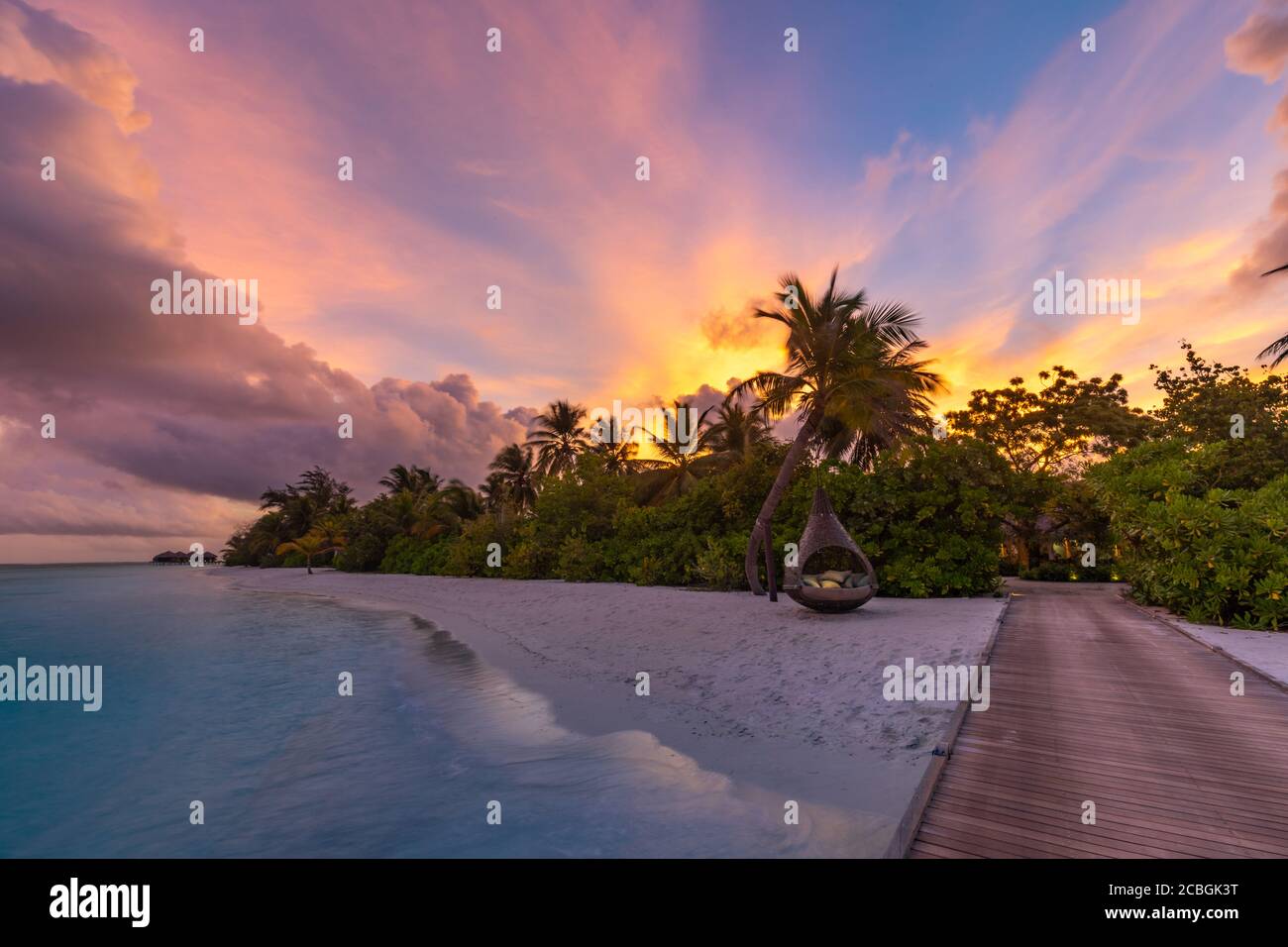 Sonnenuntergang auf der Insel der Malediven, Luxus-Wasservillen-Resort und hölzerner Pier. Schöne Himmel Wolken und Palmen Strand Hintergrund für Sommerurlaub Stockfoto