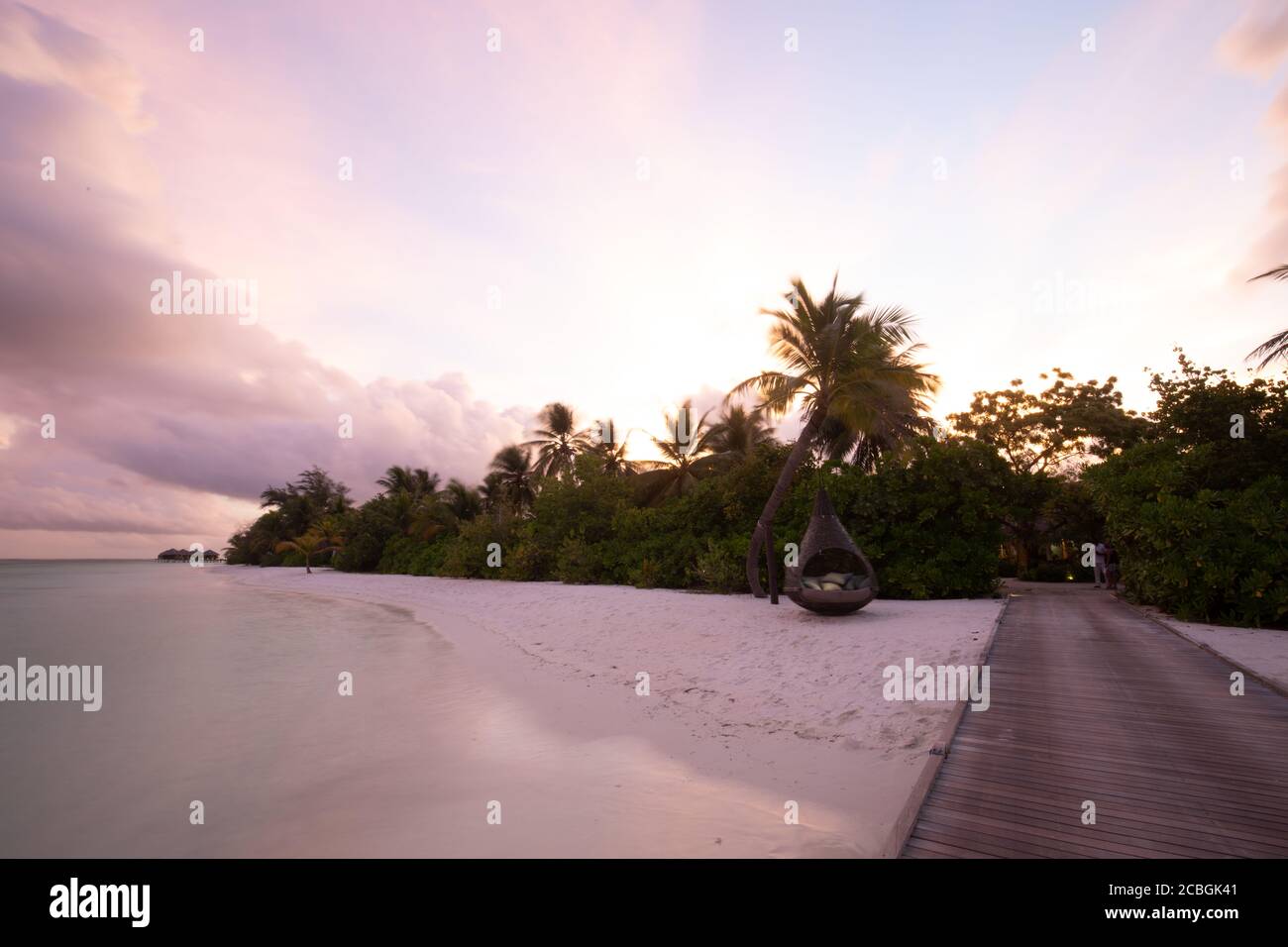 Sonnenuntergang auf der Insel der Malediven, Luxus-Wasservillen-Resort und hölzerner Pier. Schöne Himmel Wolken und Palmen Strand Hintergrund für Sommerurlaub Stockfoto