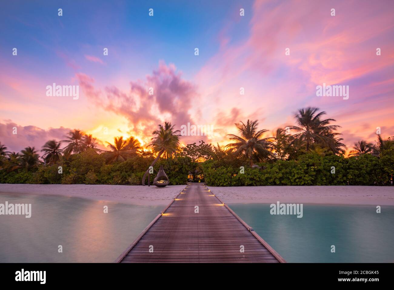 Sonnenuntergang auf der Insel der Malediven, Luxus-Wasservillen-Resort und hölzerner Pier. Schöne Himmel Wolken und Palmen Strand Hintergrund für Sommerurlaub Stockfoto