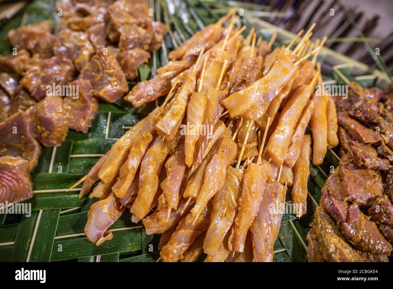 Gegrillter Fisch auf Spieße serviert auf Palmblättern Tisch in der Nähe von oben mit Kopieplatz. Fischspieße auf Palmblättern, traditionelle Mahlzeit Stockfoto