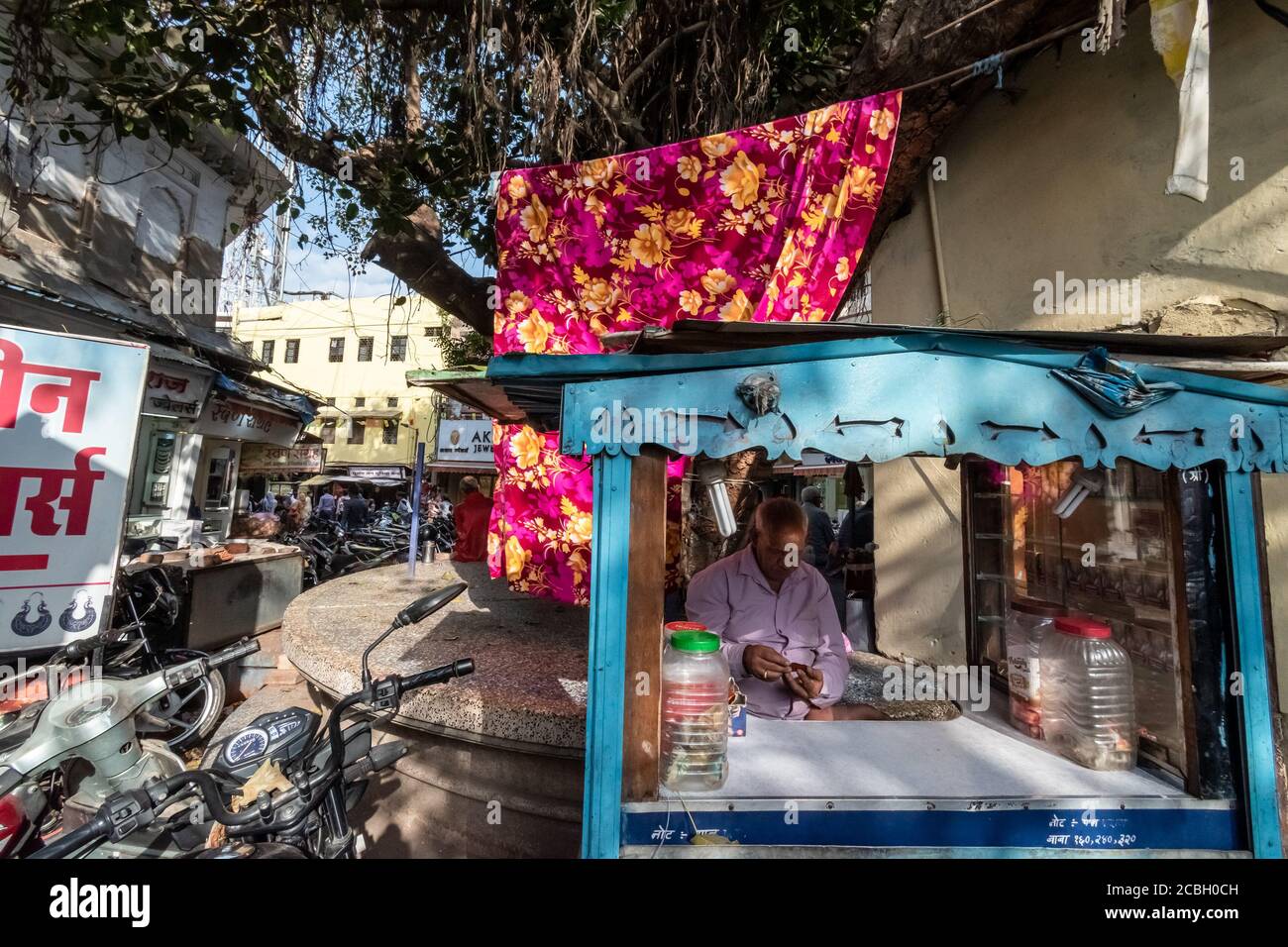 Bhopal, Madhya Pradesh, Indien - März 2019: Ein indischer Straßenverkäufer an seinem Straßenrand Stand mit einem bunten Vorhang auf der Rückseite. Stockfoto