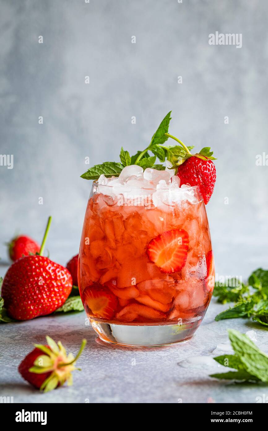 Erdbeer Mojito. Mocktail oder Coctail mit Erdbeeren und Minzblättern. Das erfrischende rote Getränk ist auf einem grauen Hintergrund mit Kopierplatz oben. Stockfoto